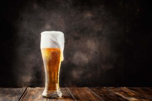 Glass of fresh and cold beer on dark background. Copy space.